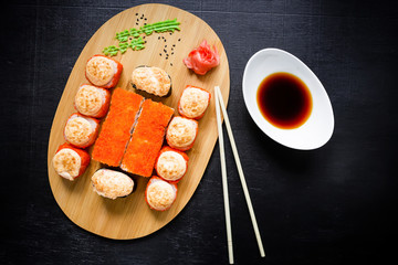 Japanese natural food. Sushi rolls, mussels, soy sauce and chopsticks on a black background. Top view. Flat lay.