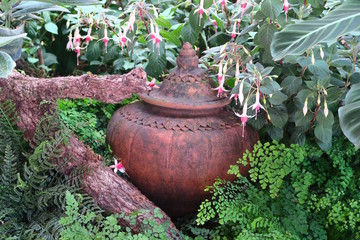 clay pot hidden under the flowers in a garden