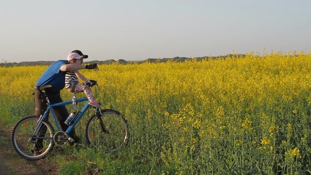A man with a child on a bicycle. Dad and daughter in nature. Dad explains to the child. Sport family. Lifestyle.