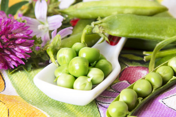Spoon of green peas on colorful tablecloth
