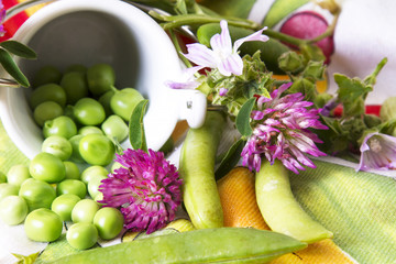 Green peas on colorful tablecloth and flowers
