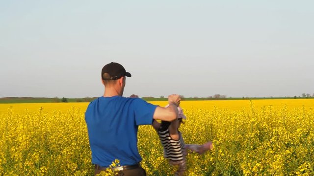 A man is turning a child. Happy father with daughter in nature.