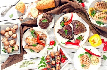Assorted grilled meats and vegetables on  wooden background.