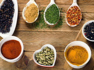 Various colorful spices on white wooden board.