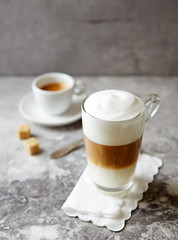 Glass of Latte Macchiato and a cup of espresso on stone background