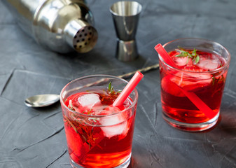 Red drink with ice. Cocktail making bar tools, strawberry and thyme leaves