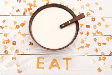 Close-up view of milk and spoon in bowl, word eat from breakfast cereal letters and alphabet corn...