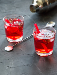 Red drink with ice. Cocktail making bar tools, strawberry and thyme leaves