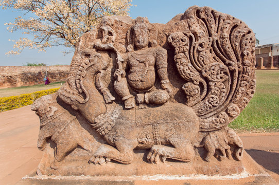 Ancient Hindu god sitting on myth lion creature, ruins of stone relief carvings from the 7th century temple's wall, Aihole town of Karnataka. Old Indian artwork.