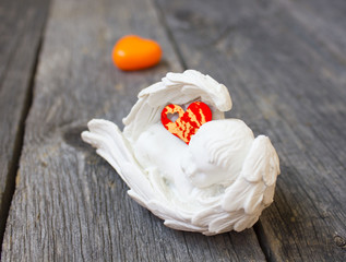 statuette of an angel with hearts on wooden background