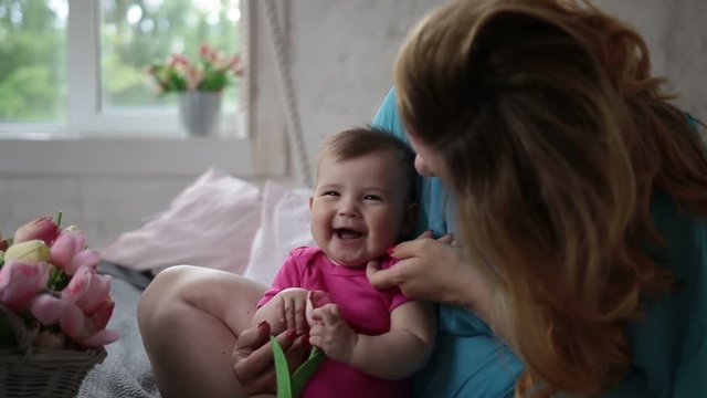 Laughing baby girl and mother relaxing in bedroom
