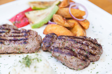 Grilled beef steak. Beef steak on a white plate. Steak with grilled vegetables isolated on white background. 