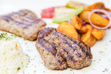 Grilled beef steak. Beef steak on a white plate. Steak with grilled vegetables isolated on white background. 