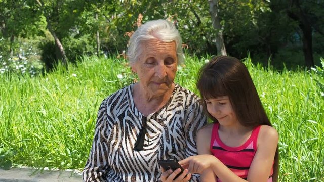 Family with telephone phone. Happy granddaughter shows grandmother a mobile phone.