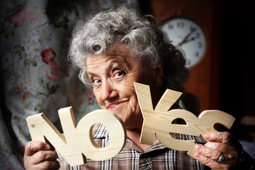 Elderly woman with wood word "Yes" and "No"