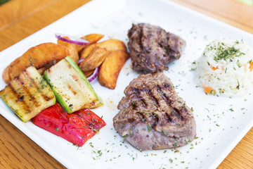 Grilled beef steak. Beef steak on a white plate. Steak with grilled vegetables isolated on white background. 