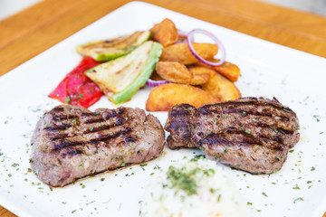 Grilled beef steak. Beef steak on a white plate. Steak with grilled vegetables isolated on white background. 