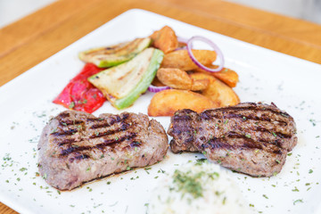 Grilled beef steak. Beef steak on a white plate. Steak with grilled vegetables isolated on white background. 