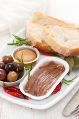 anchovies, olives, bread and fish pate on dish