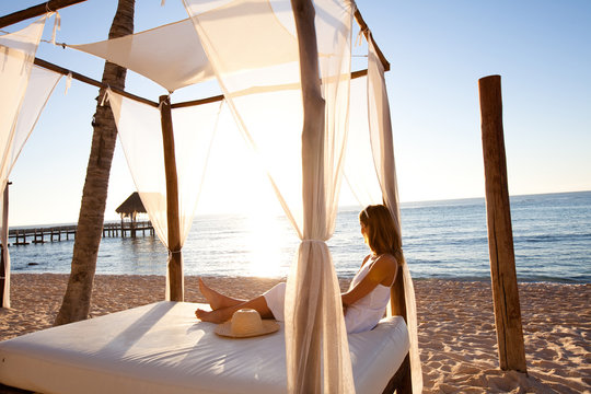 femme se relaxant sur un lit en bambou sur la plage