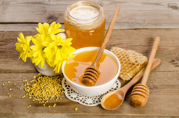 Yellow flowers and bee products (honey, pollen, honeycombs) on wooden background