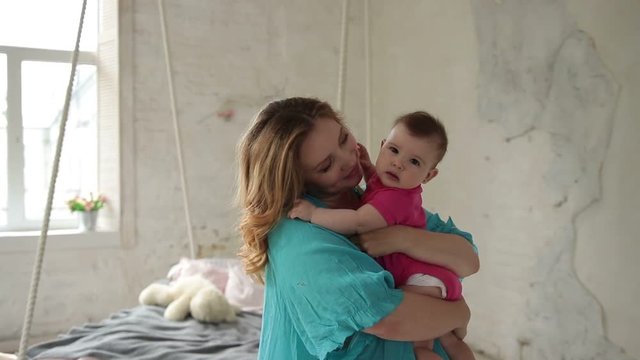 Caring young mom nursing infant child at home.