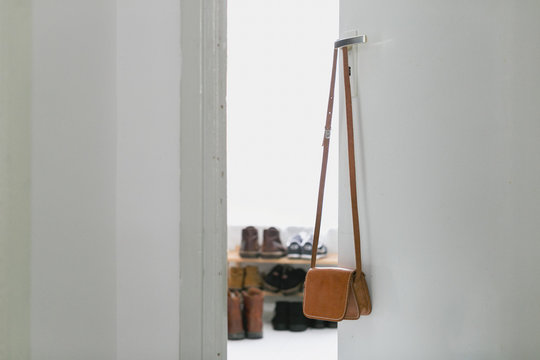 a small leather purse hangs on a door handle