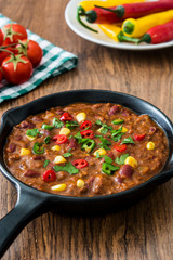 Traditional mexican tex mex chili con carne in a frying pan on wooden table
