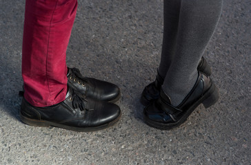 Fototapeta na wymiar Valentine's Day legs man and woman couple pants asphalt shoes sandals manicure. Black elegant lether shoes.