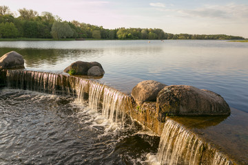 Waterfall on the lake in the spring evening