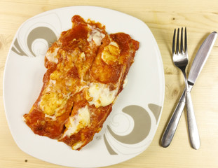 Salt crepes and tomato sauce on wooden background - top view