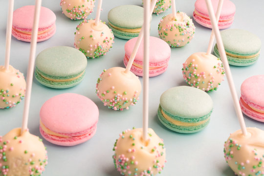 Tasty mint and strawberry flavor macarons and cake pops on sticks on blue background