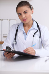 Fototapeta na wymiar Doctor woman filling up medical form while sitting at the desk. Medicine and health care concept