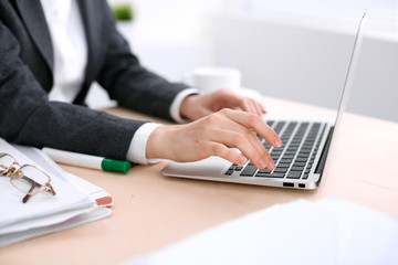 Close up of business woman hands typing on laptop computer in the white colored office