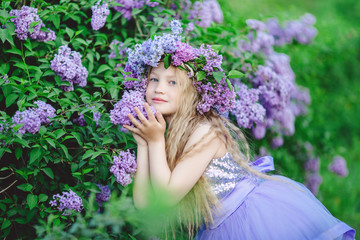 Beautiful child girl with wreath of lilac flowers