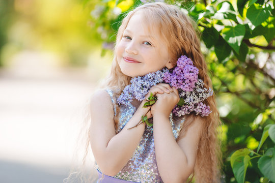 Beautiful child girl with bouquet of lilac flowers