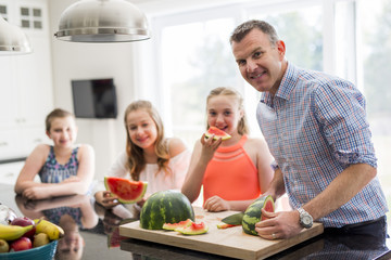 family in the kitchen cuting the watermelon