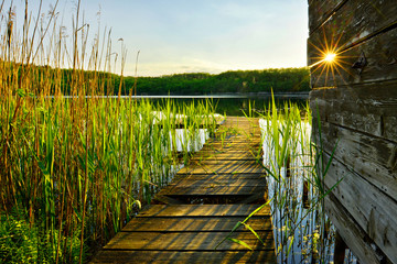 Abends am See, ein letzter Sonnenstrahl auf Steg und Schilf