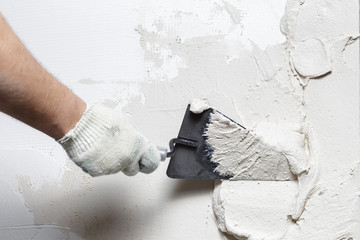 Construction worker puts a gypsum on the wall with a spatula - obrazy, fototapety, plakaty
