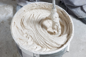 Builder mixing plaster in a bucket using an electric mixer