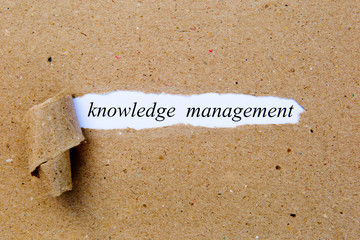 Knowledge Management - printed text underneath torn brown paper
