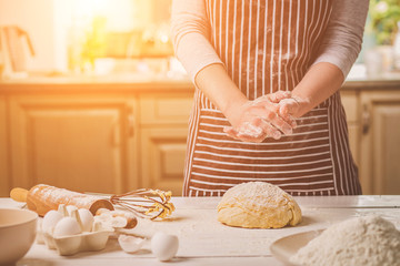Woman slap his hands above dough closeup. Baker finishing his bakery, shake flour from his hands,...