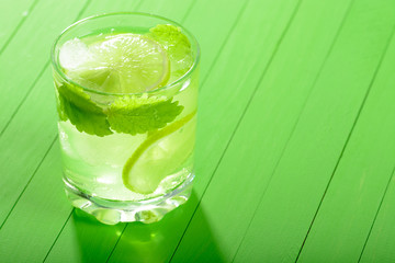 A glass of Mojito with ice, limes and mint on wooden boards
