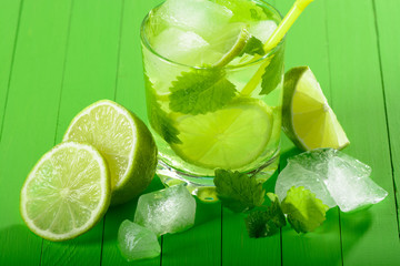 A glass of Mojito with ice, limes and mint on wooden boards