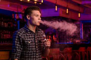 Fototapeta premium The man smoke an electronic cigarette at the vape shop.