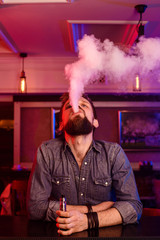Vape. Vaping man in a cloud of vapor. Photo is taken in a vape bar.