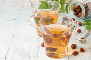   Freshly prepared infusion of dry fruit rose hips in glass transparent mug on a light wooden background.