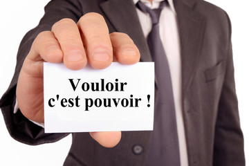 Homme tenant une carte avec vouloir c'est pouvoir écrit dessus 