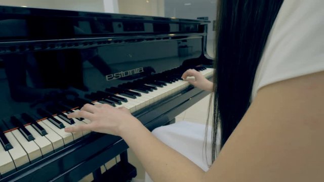 Unrecognised girl playing the piano. Steadicam. Close-up. 4K.