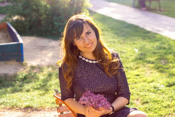 Young girl in the spring evening in a park with lilac flowers.